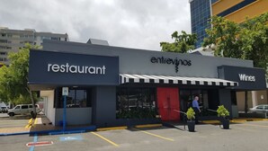 Un restaurante con un letrero que dice 'restaurant', un letrero que dice 'Wines' y un área de estar al aire libre cubierta.