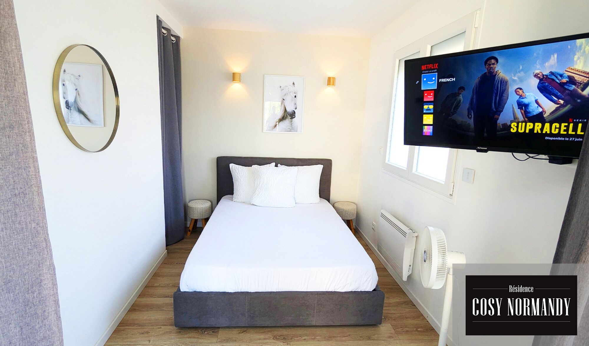 Ein Schlafzimmer mit einem Bett, einem an der Wand befestigten Fernseher und einem Fenster.
