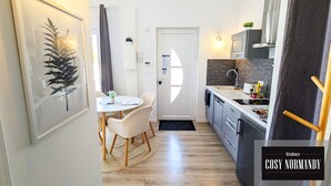 Una cocina compacta con comedor, una puerta blanca y un ventanal pequeño.