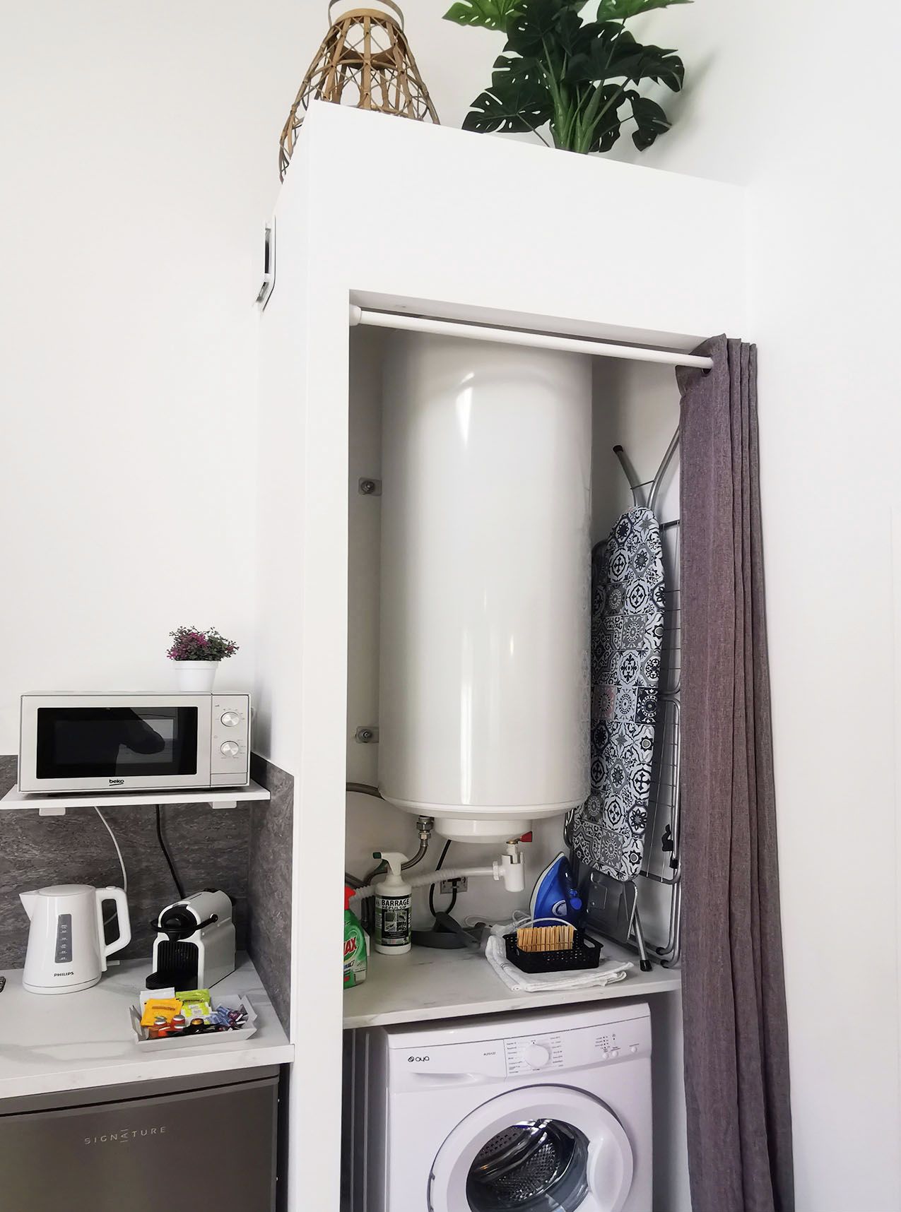 Une cuisine compacte équipée d’un four à micro-ondes, d’une bouilloire et d’un lave-linge.