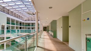 Ein modernes Interieur mit einer gläsernen Wendeltreppe, Holzboden und einer hohen Decke mit Dachfenstern.