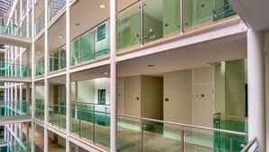 Ein mehrgeschossiges Atrium mit Glasgeländern und Holzboden.