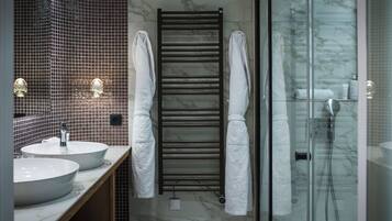 A modern bathroom with two sinks, a towel rack, and a glass shower enclosure.