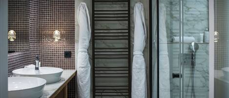 Une salle de bain moderne avec deux lavabos, un porte-serviettes et une cabine de douche en verre.