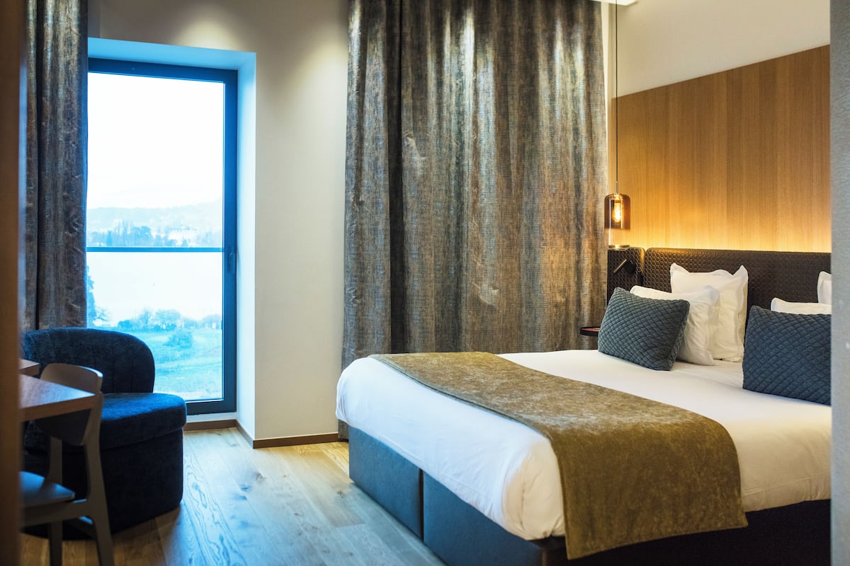 Habitación de hotel con una cama grande, un escritorio y vistas a una masa de agua a través de una ventana.