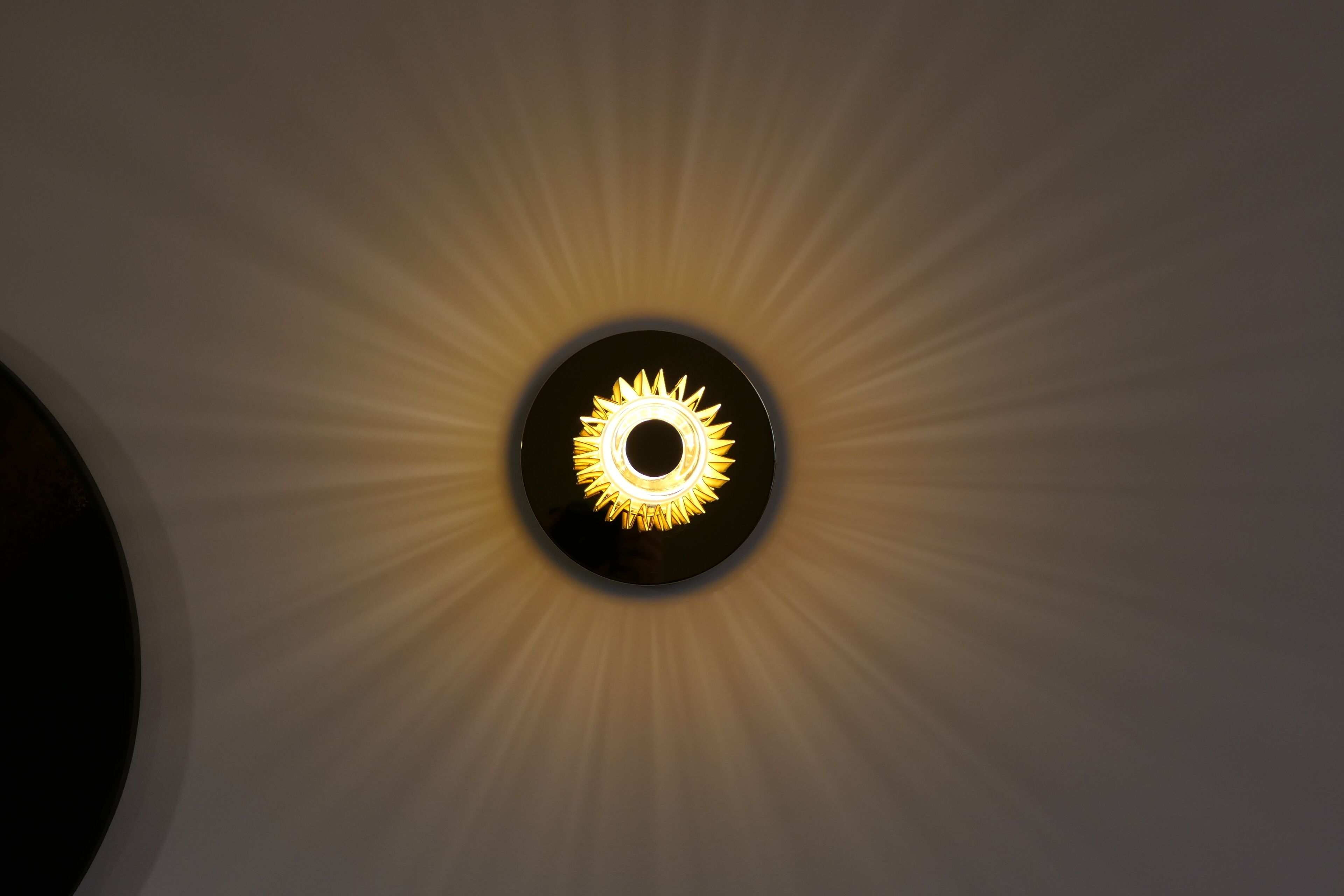 Un luminaire de plafond circulaire, dont le design évoque un soleil.