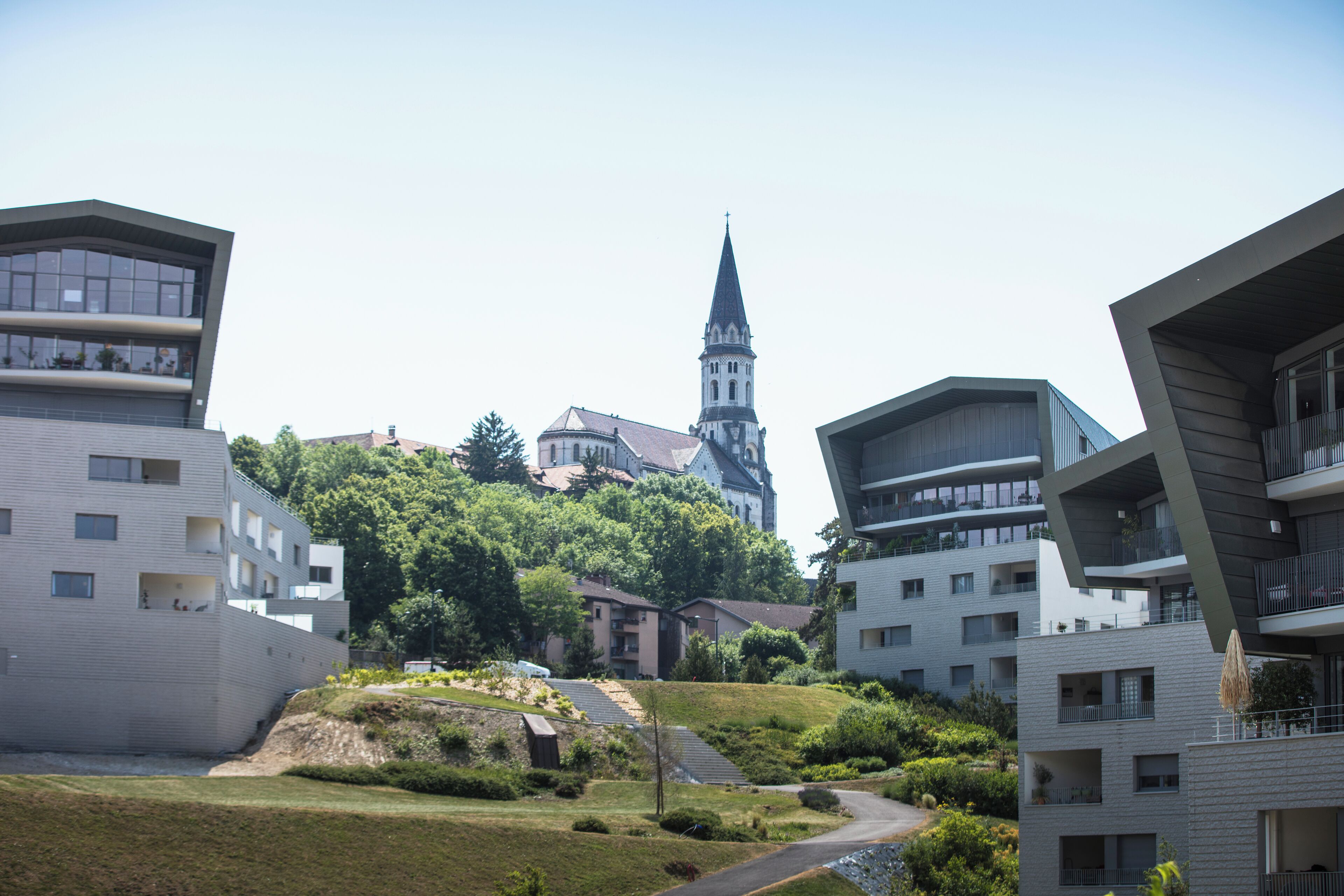 A modern residential area with contemporary buildings, a church with a tall spire, and a well-maintained green space.
