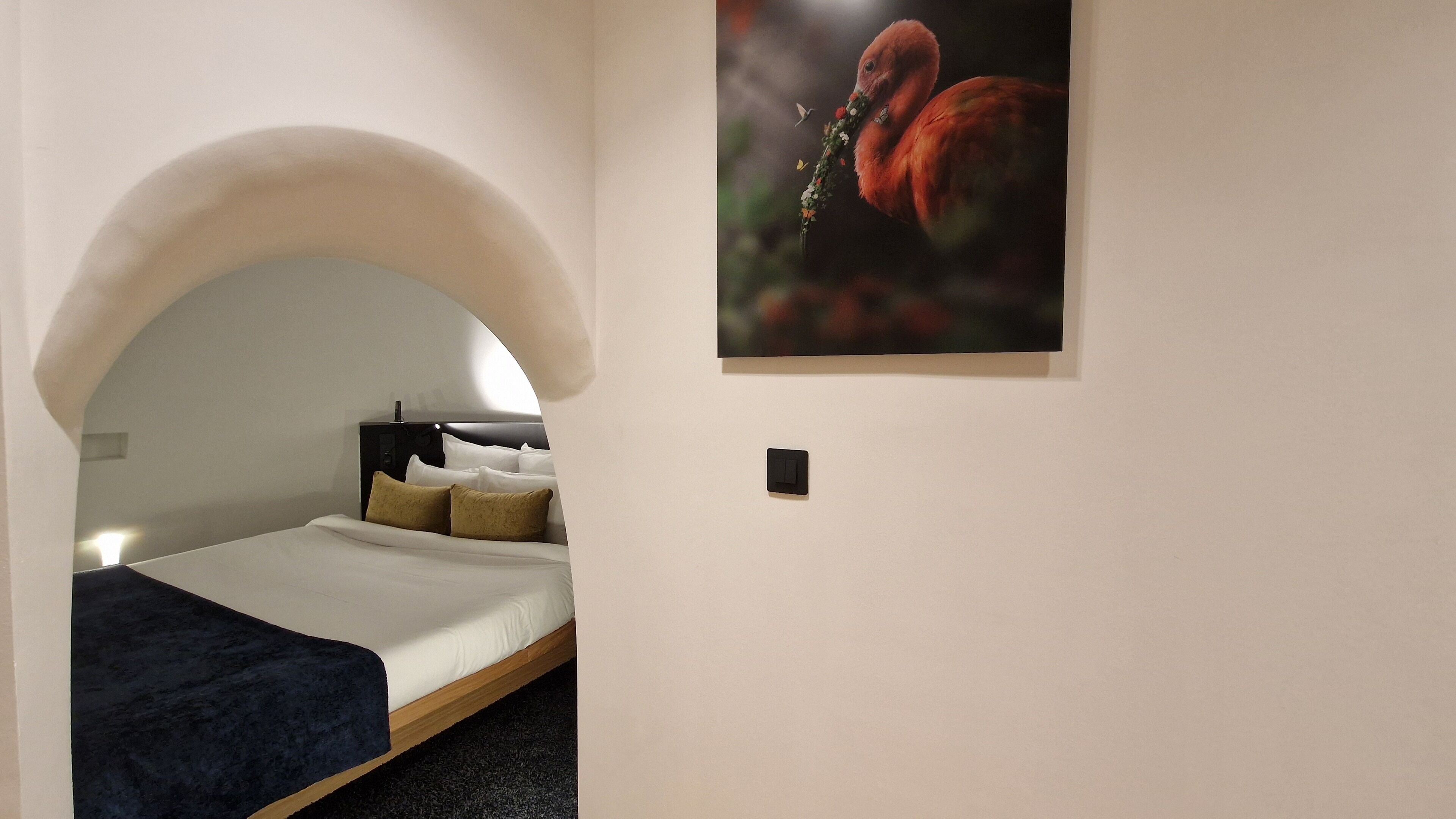 A bedroom with a bed, a nightstand, and a wall-mounted light.