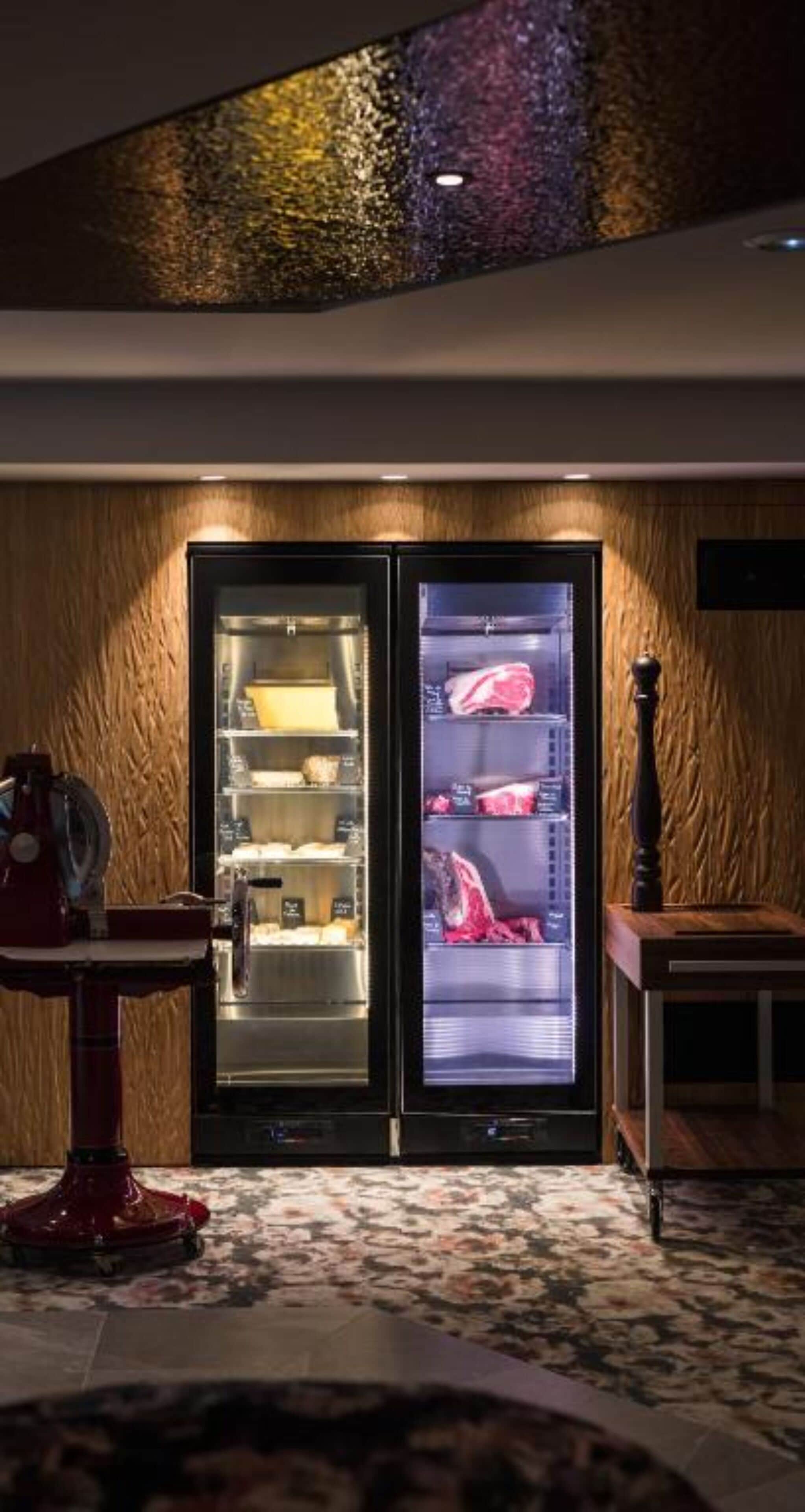 A modern kitchen with two refrigerators, a coffee machine, and a wooden wall.