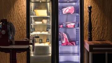 A modern kitchen with two refrigerators, a coffee machine, and a wooden wall.