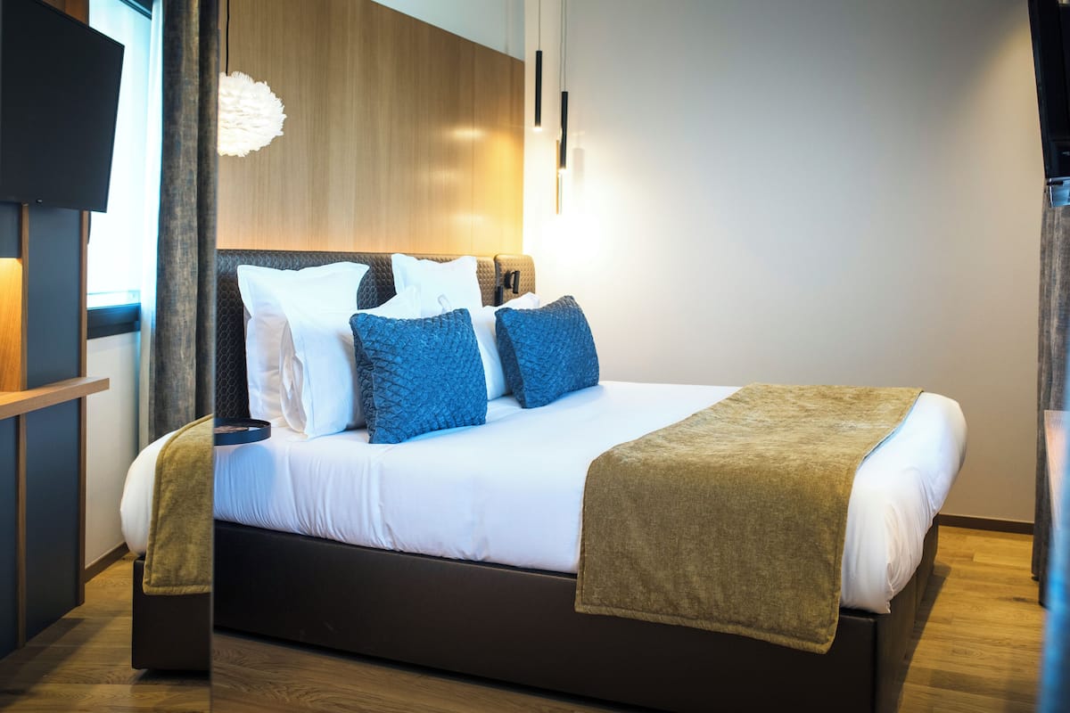 Una habitación de hotel moderna con una cama grande, un televisor de pantalla plana y un cabecero de madera.