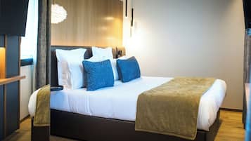 A modern hotel room with a large bed, a flat-screen TV, and a wooden headboard.