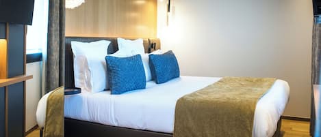 Ein modernes Hotelzimmer mit einem großen Bett, einem Flachbildfernseher und einem hölzernen Kopfteil.