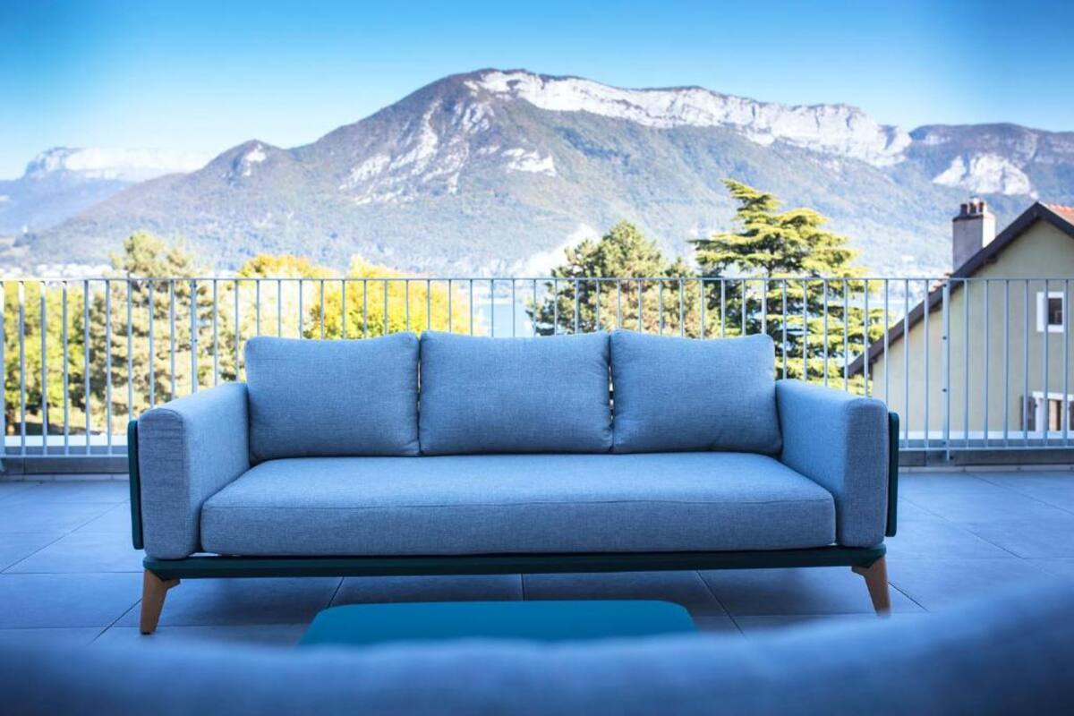 Un sofá azul en un balcón con vistas a la montaña.