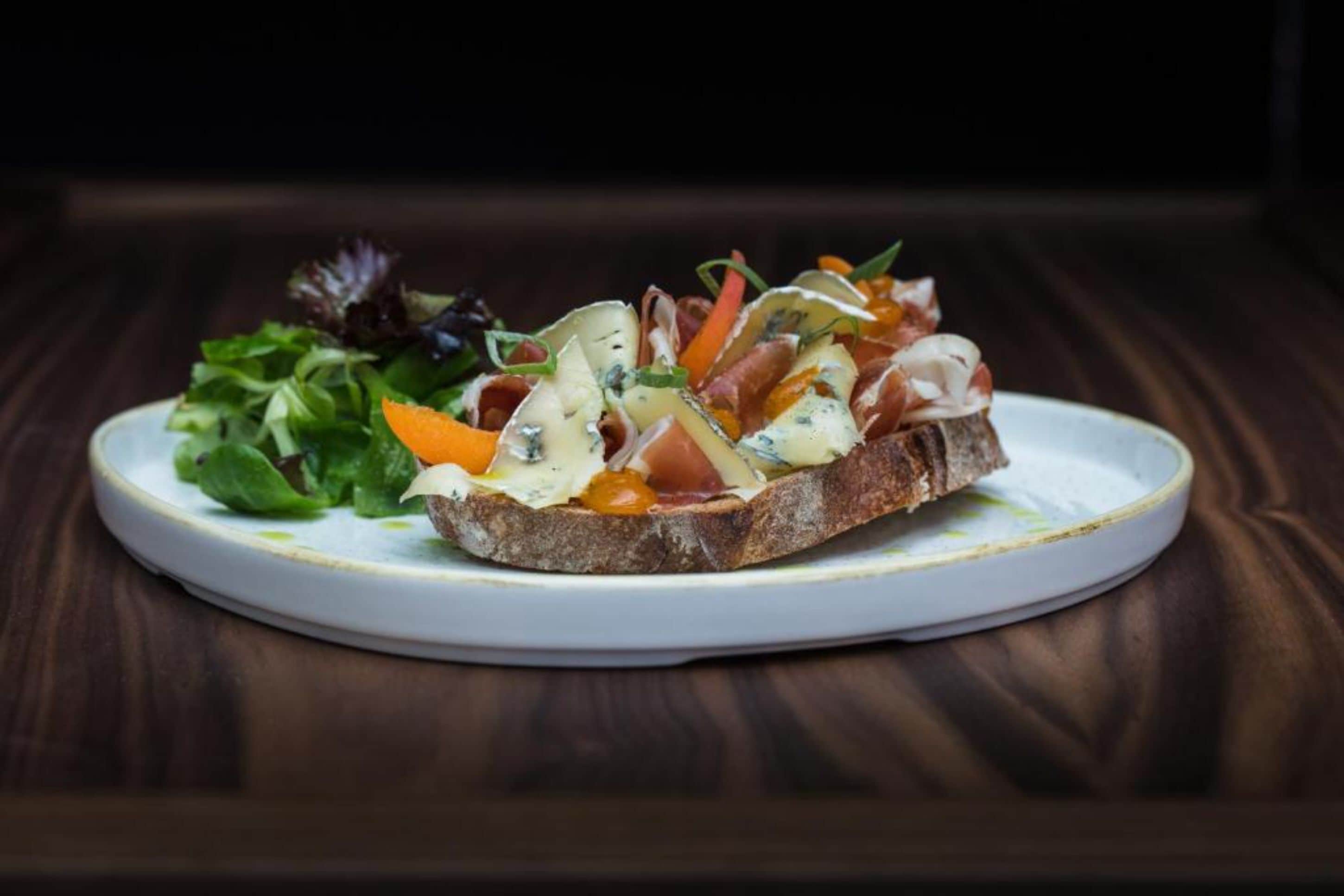 A plate with a sandwich and a side salad on a white plate.