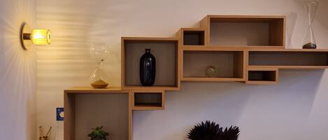 A wall with a wooden shelf unit containing various decorative items.