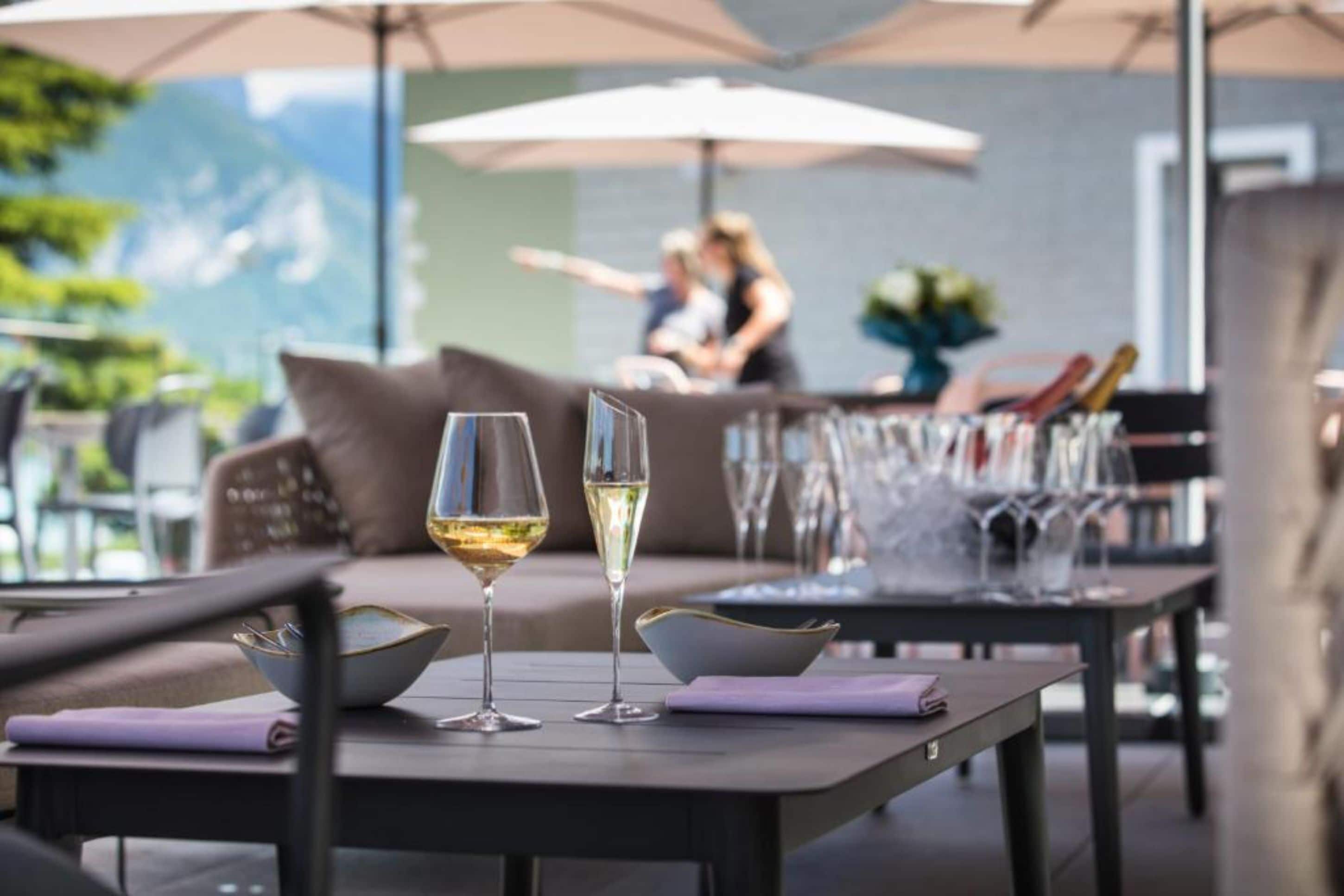 An outdoor dining area with tables and chairs, a sofa, and umbrellas.