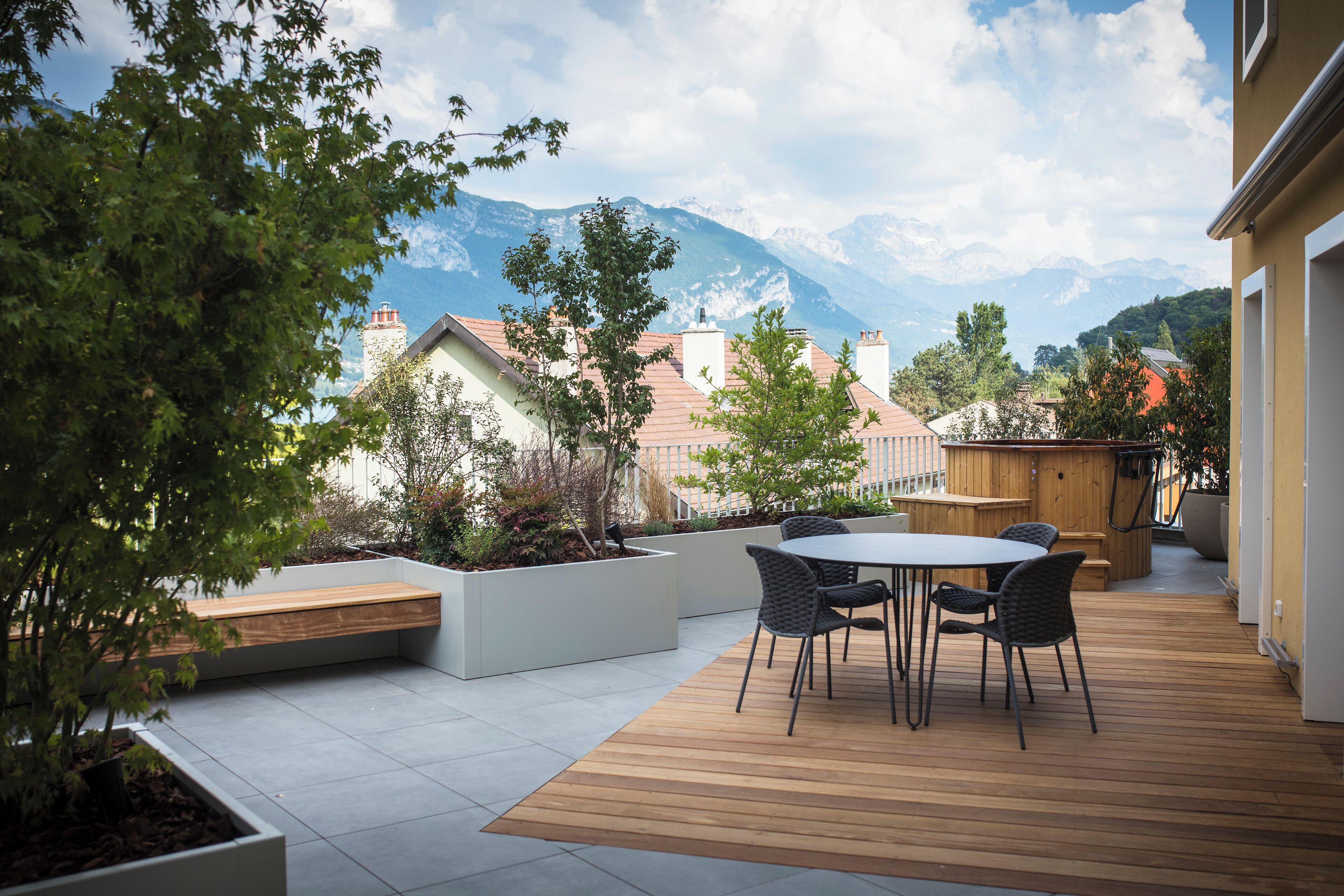 A patio with a wooden deck, a round table, and chairs.