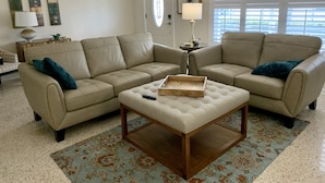 Ein Wohnzimmer mit zwei beigen Sofas, einem Holztisch und einem gemusterten Teppich.