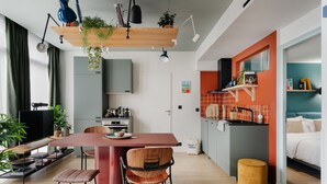 Een moderne keuken met een rode kookeiland, houten stoelen en een eettafel.