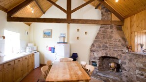 Una cucina rustica con camino in pietra, travi in legno e un tavolo da pranzo.