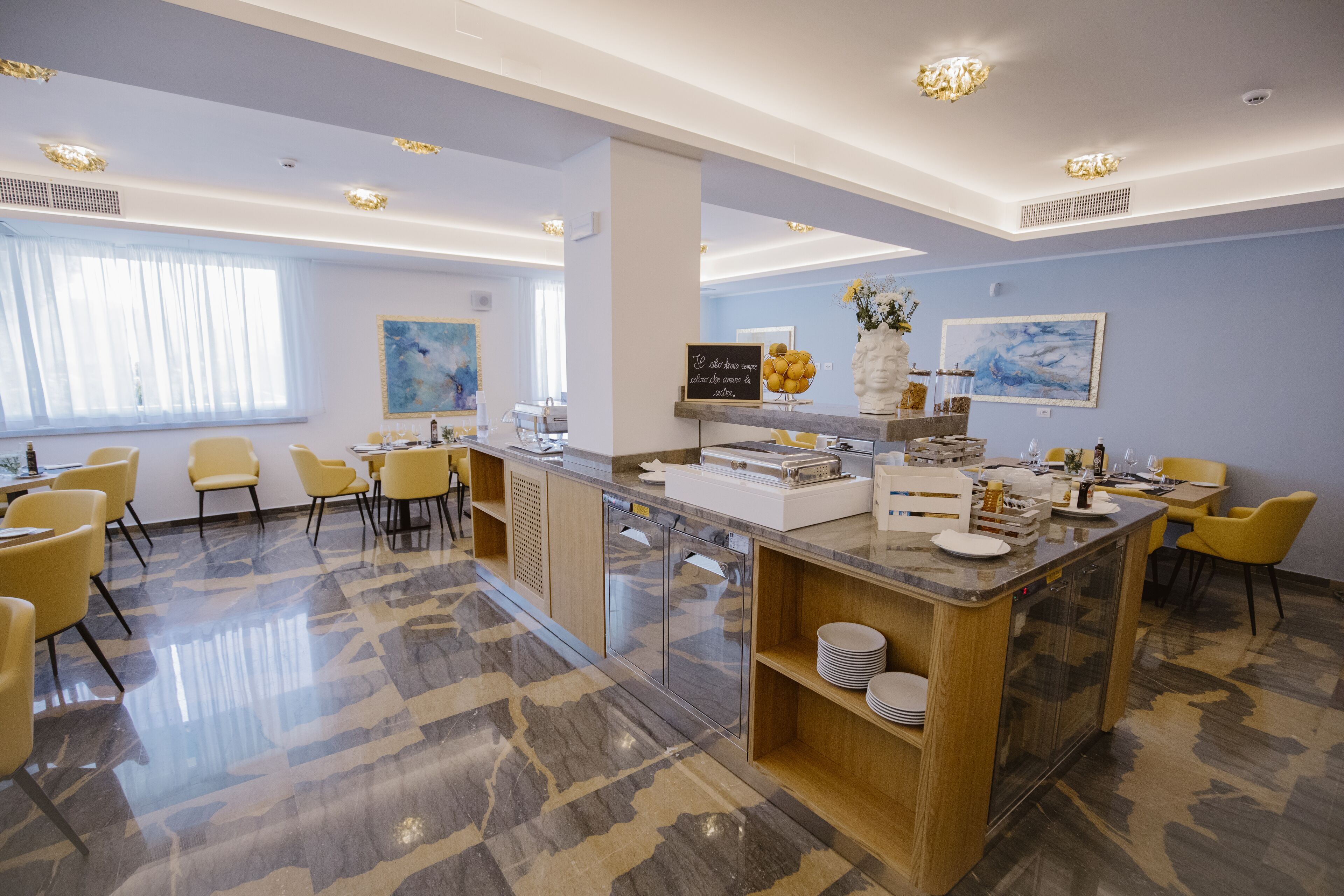 A modern hotel lobby with a central island, seating area, and artwork on the walls.