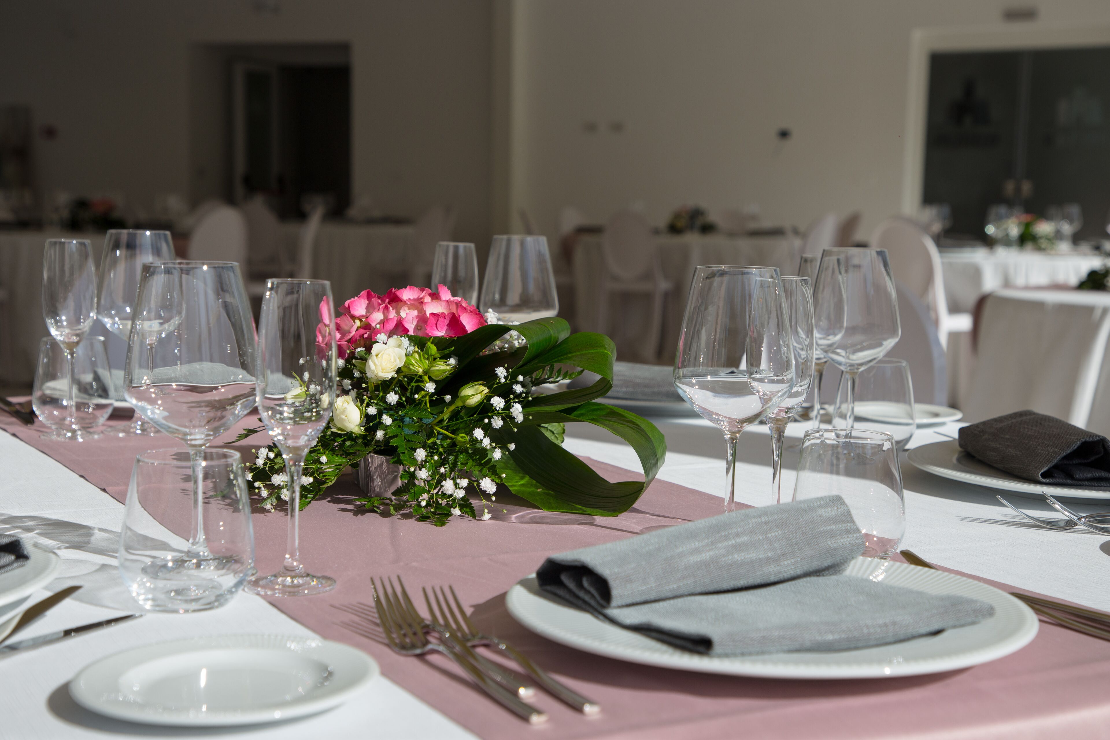 A table set for a formal event with multiple wine glasses, plates, and cutlery.