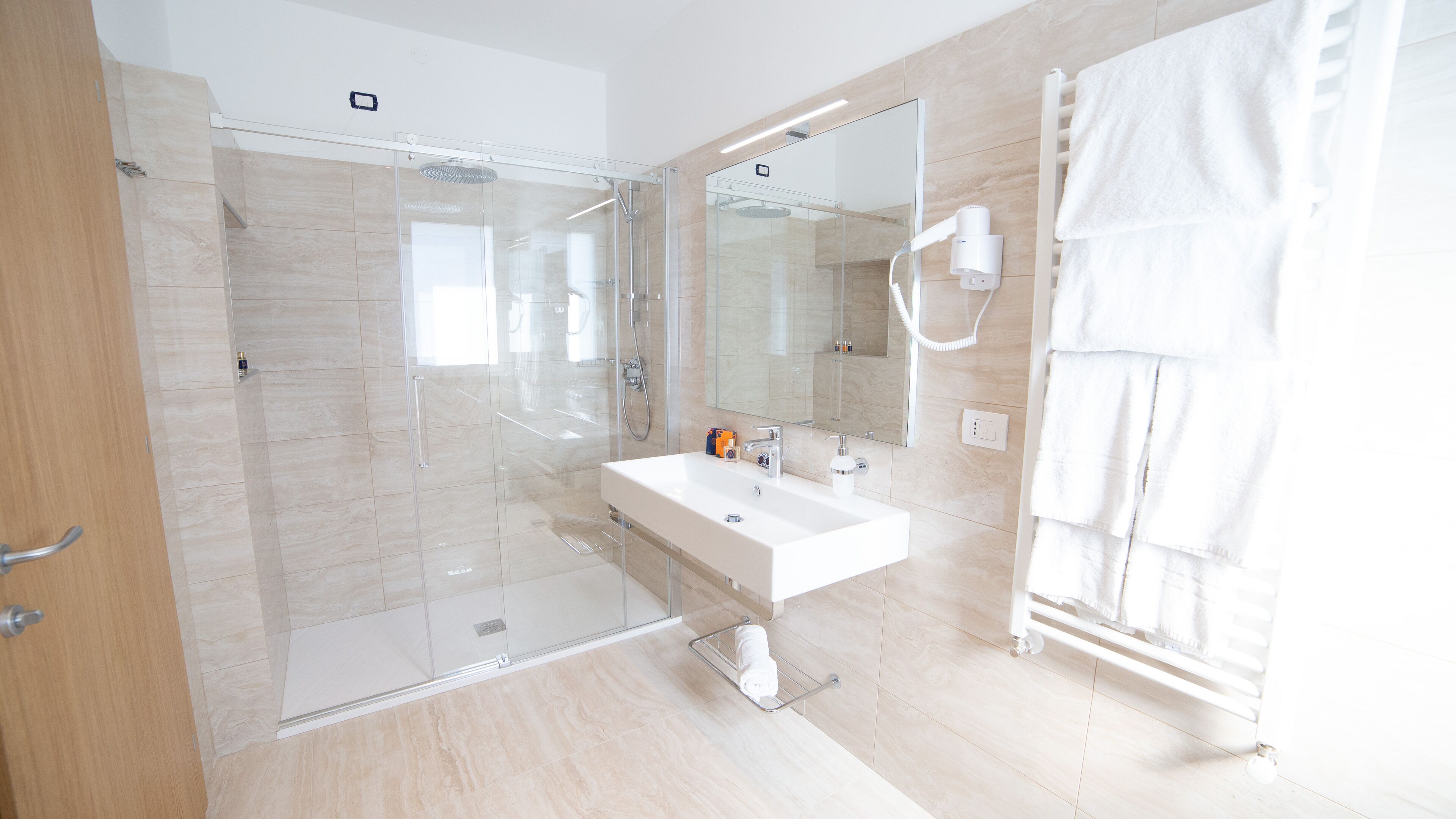 A modern bathroom with a glass-enclosed shower, a white sink, and a towel rack.