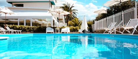 Piscine couverte, piscine extérieure, parasols de plage, chaises longues