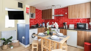 Cozinha compacta com máquina de lavar, micro-ondas e painel de azulejos vermelhos.