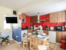 A compact kitchen with a washing machine, microwave, and red tiled backsplash.