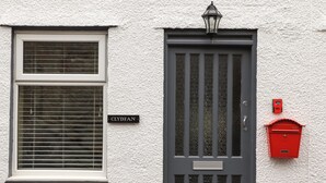 Uma casa com fachada branca, porta cinza com janela e caixa de correio vermelha.