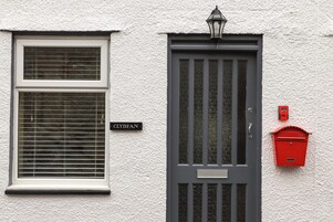 A house with a white exterior, a grey door with a window, and a red mailbox.