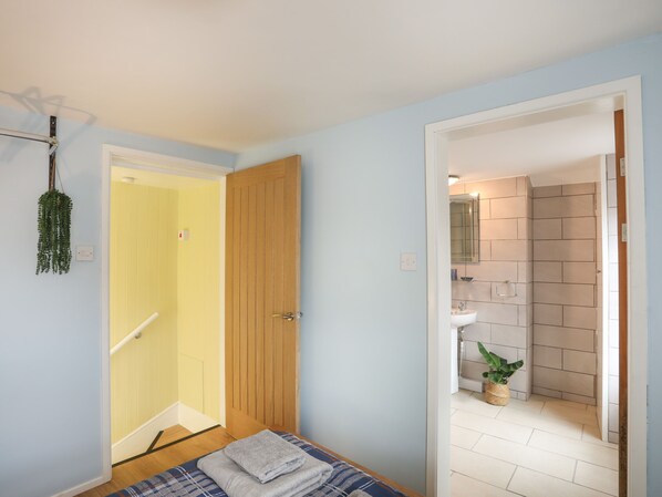 A bedroom with a bed, a wooden door, and a bathroom visible through an open door. - Clydfan (Caernarfon)