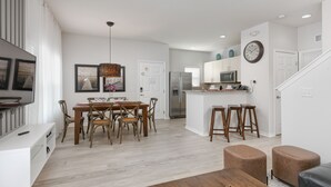 Una cocina moderna con armarios blancos, un refrigerador de acero inoxidable y un microondas.