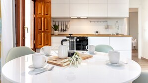Una cocina moderna con armarios blancos, una cafetera y una tabla de madera con flores.