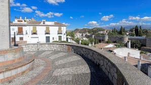 Un anfiteatro de piedra con un área de asientos curvada, rodeado por un muro de piedra.