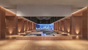 A spacious lobby with a central water feature, brick walls, and a modern ceiling design.