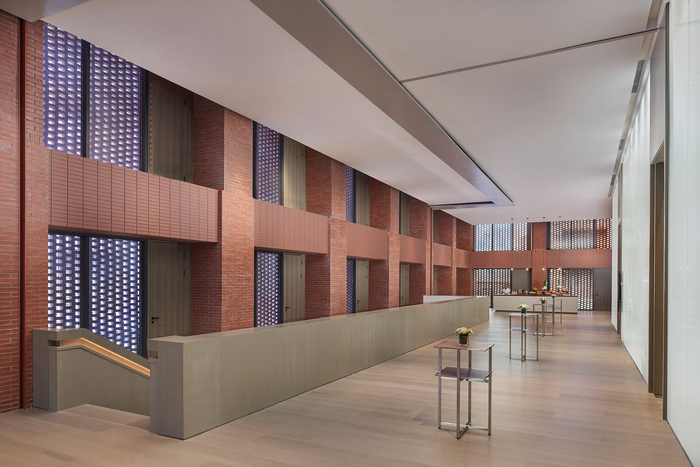 A modern interior with a long corridor, brick walls, and a central walkway.