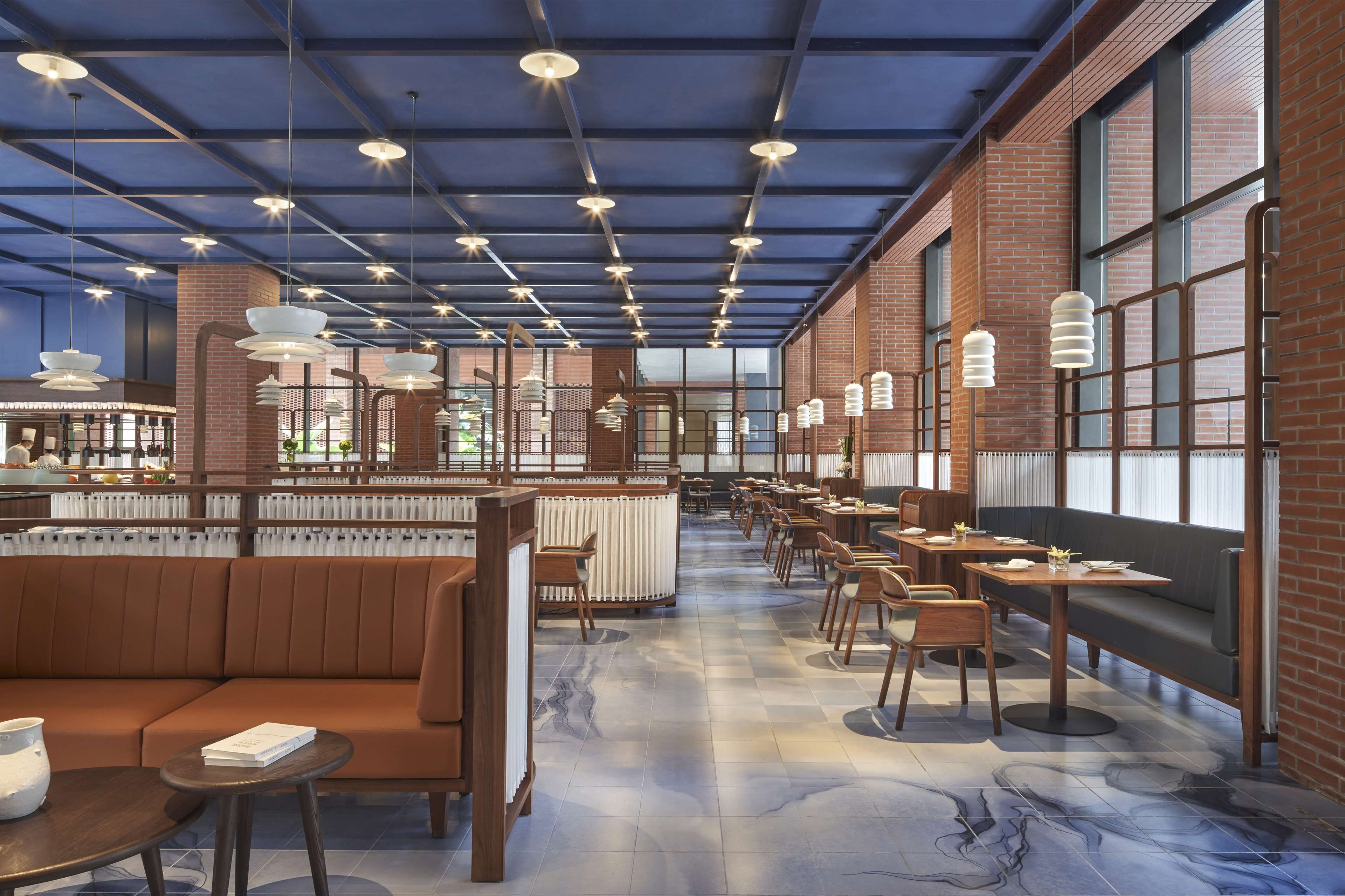 Un vaste espace intérieur aménagé avec des coins salon, des tables et des luminaires suspendus.