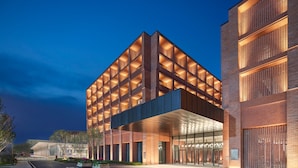 A modern building with a grid-like facade, large glass entrance, and a well-lit entrance area.