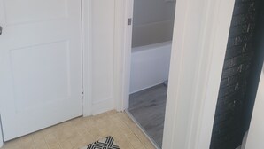 Een kamer met een witte deur, een kamerbreed tapijt met dessin en een muur van zwarte baksteen.