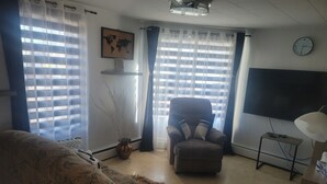 Een woonkamer met een bank, een stoel, een televisie en een wereldkaart aan de muur.