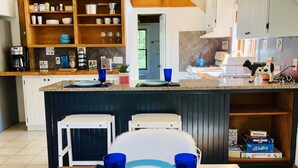 Una cocina moderna con detalles de madera, un comedor con vajilla azul y un dormitorio en loft con vistas.