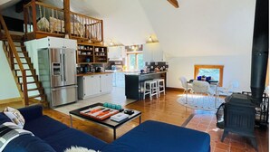 Un amplio espacio tipo loft con techo alto, vigas de madera, una cocina moderna y una zona de estar acogedora.