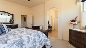 Une chambre à coucher avec un lit, une commode et un ventilateur de plafond.