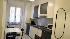 Eine kleine Küche mit Esstisch und Stühlen, einer Mikrowelle und einem schwarzen Backofen.