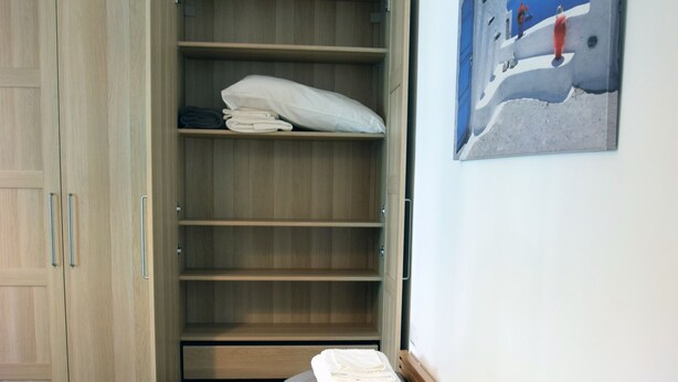 Ein Schlafzimmer mit einem Bett, einem Kleiderschrank und einem Bild an der Wand.