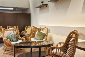 A room with wicker furniture, a round table, and a sofa. - Neuchatel City Hotel (Neuchatel)