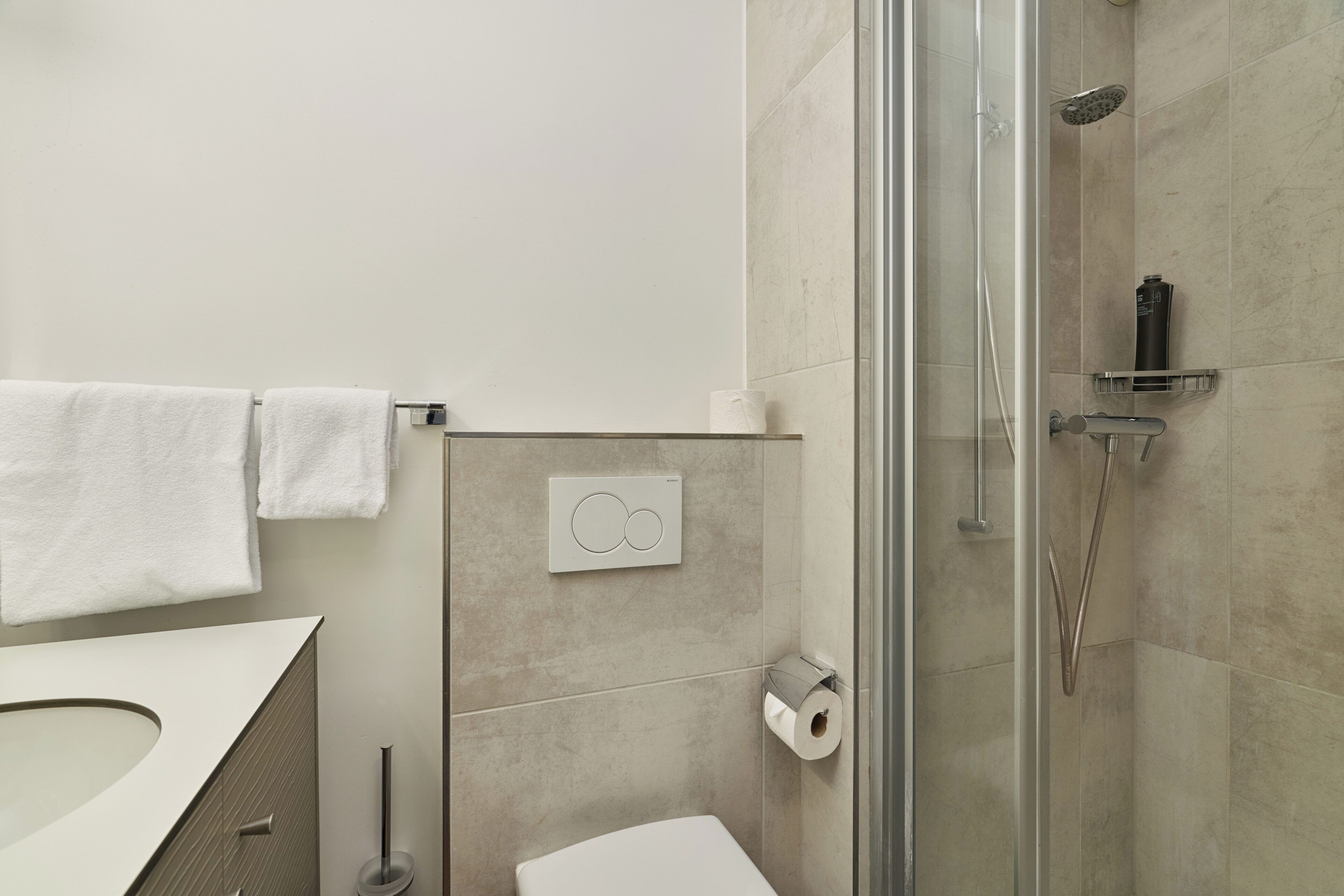 Un baño moderno con ducha, inodoro y un perchero para toallas.